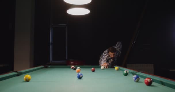 Un homme joue au billard seul sous des lumières tamisées dans un club de billard — Video