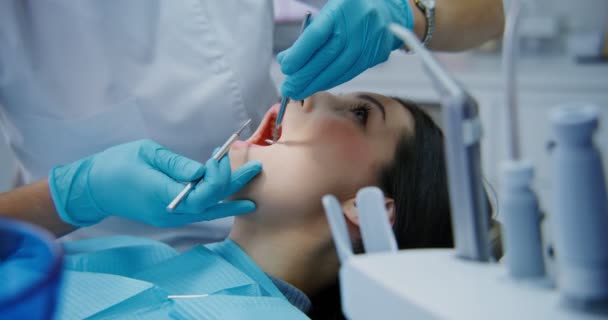 Zubař vezme lékařský nástroj a vyšetření ústní dutiny ženy — Stock video