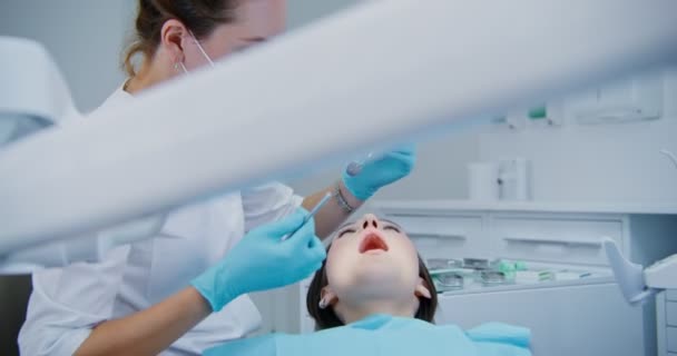 El dentista toma un instrumento médico y comienza un examen de los pacientes — Vídeos de Stock