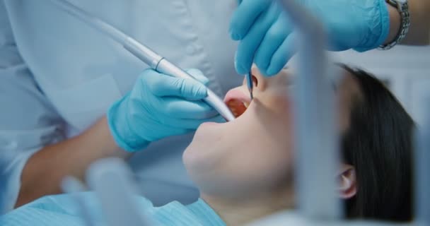 Un dentista toma una máquina para perforar dientes y comienza el tratamiento — Vídeos de Stock