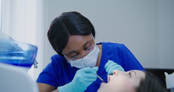 Afričanky americká žena zubař zkoumá ústní dutiny ženy — Stock video