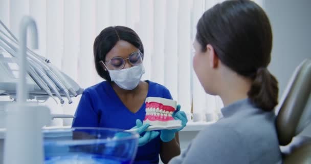 Afrikai amerikai fogorvos bemutatja a betegnek, hogyan kell megfelelően fogat mosni — Stock videók