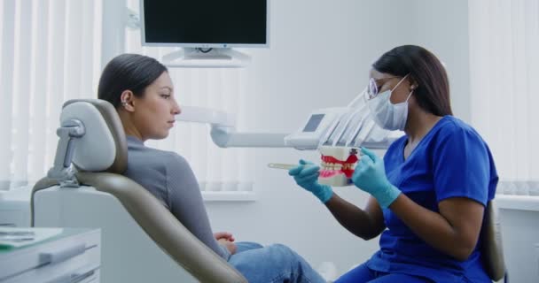 African american dentist demonstrates to patient how to properly brush teeth — Stock Video