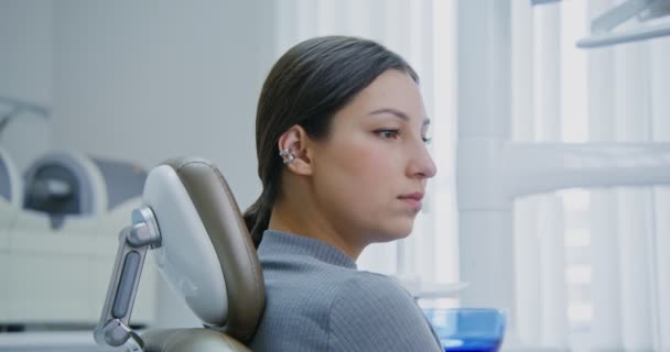 Una paciente sentada en una silla dental escucha las instrucciones del médico — Vídeo de stock