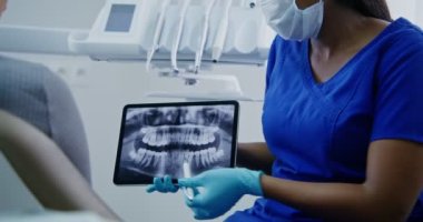 Bir dişçi, bir kadın hastaya tablet kullanan bir diş fotoğrafını gösterir.