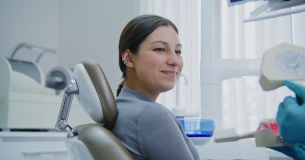 Eine Patientin, die im Zahnarztstuhl sitzt, hört den Anweisungen des Arztes zu — Stockvideo