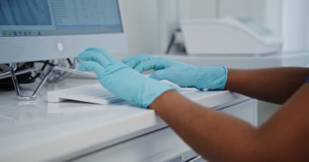 Un medico in guanti blu usa e getta sta digitando su una tastiera del computer — Video Stock