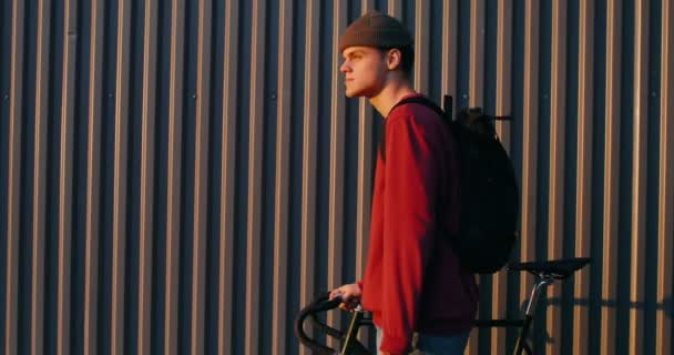 Ένας νεαρός οδηγεί ένα ποδήλατο στα χέρια του, κάνοντας βόλτες στην πόλη. — Αρχείο Βίντεο