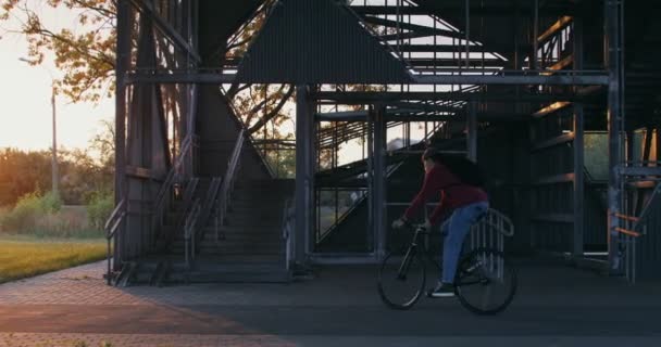 A man rides a bicycle to ladder, takes bicycle in his arms and carries it up — Stock Video