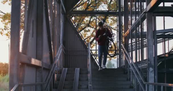 男ははしごに自転車に乗り、腕に自転車を乗せて運ぶ。 — ストック動画
