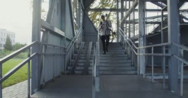 Bir adam merdivene bisikletle gider, bisikleti kollarına alır ve yukarı taşır.