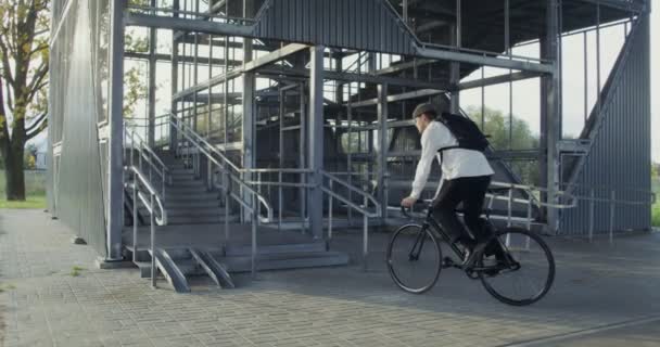 A man rides a bicycle to ladder, takes bicycle in his arms and carries it up — Stock Video