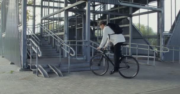 Ένας άντρας οδηγεί ένα ποδήλατο στη σκάλα, παίρνει το ποδήλατο στην αγκαλιά του και το ανεβάζει. — Αρχείο Βίντεο