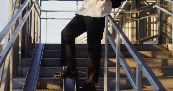 Een man gebruikt een mobiele telefoon en drinkt koffie staande op een metalen trap — Stockvideo