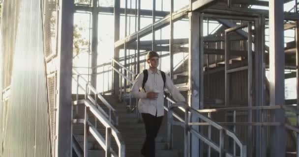 A young man descends a metal staircase, holding a cup of coffee — Stock Video