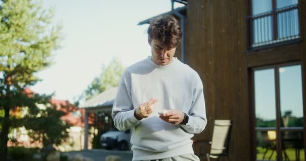 Un jeune homme en tenue de sport fait des exercices en plein air près d'un manoir moderne — Video