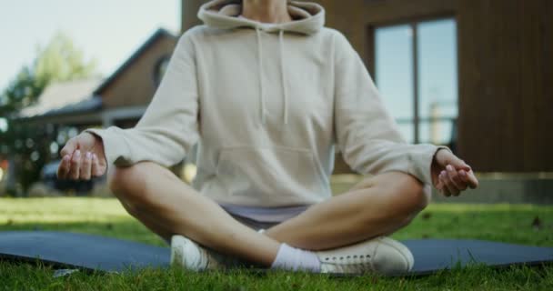 Una donna si siede su un tappeto da ginnastica in una posizione di loto all'aperto — Video Stock