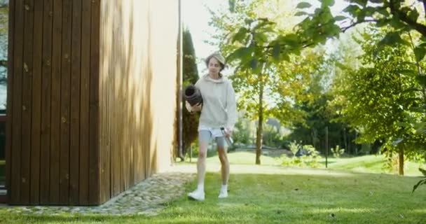 A woman leaves the house with a sports mat for outdoor sports — Stock Video