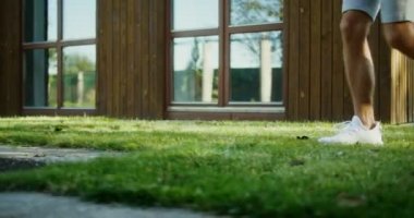 Beyaz spor ayakkabılı bir adam arka bahçeye doğru küçük bir merdiven iner.