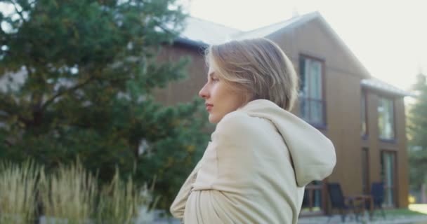 Une jeune femme en vêtements de sport fait des exercices sur la pelouse près d'un chalet moderne — Video