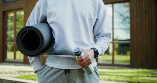 Ein Mann mit Sportmatten steht im Hinterhof bereit für den Sport — Stockvideo