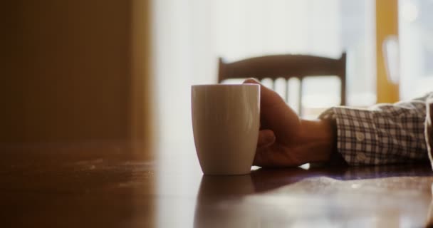Een man drinkt warme thee of koffie, stoom stijgt op uit een mok — Stockvideo
