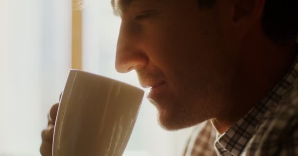 Egy férfi forró teát vagy kávét iszik, a gőz egy bögréből emelkedik ki. — Stock videók