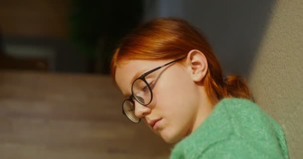 En flicka läser en bok intensivt när hon sitter på trappan i en heminredning — Stockvideo