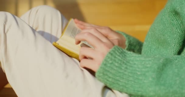 Chica leyendo un libro sentado en las escaleras, primer plano — Vídeos de Stock