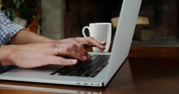 Um homem vestido com roupas casuais, está digitando em um laptop no hom — Vídeo de Stock