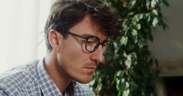 En europeisk man med glasögon stirrar på en bärbar dator. — Stockvideo