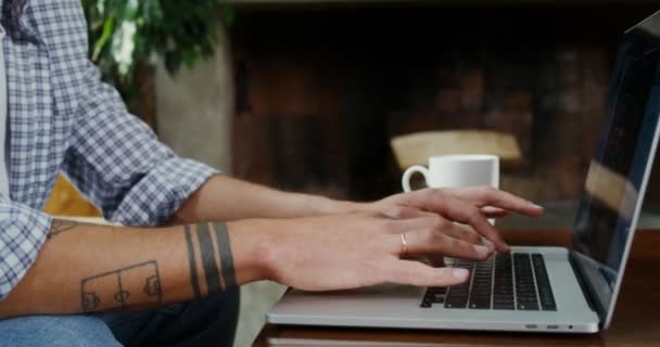 Ein Mann benutzt Laptop, während er auf einem Sofa an einem Couchtisch im modernen Interieur sitzt — Stockvideo