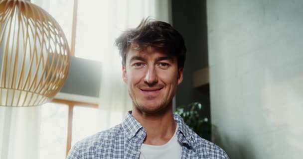 Knap jong brunette man kijken naar de camera en glimlachen — Stockvideo