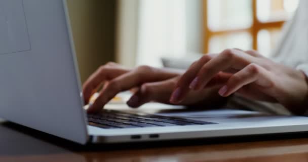 Жінка друкує на ноутбуці, сидячи за журнальним столиком — стокове відео