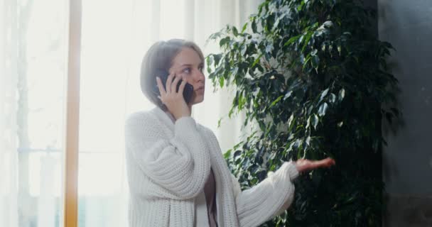 Giovane donna che parla al telefono mentre cammina per la stanza — Video Stock