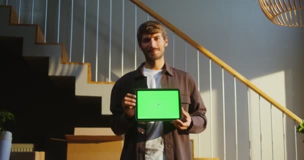 Mężczyzna uśmiecha się patrząc w kamerę i trzymając tablet z zielonym ekranem — Wideo stockowe