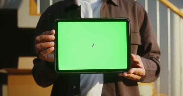 Um homem segurando um tablet com uma tela verde, close-up — Vídeo de Stock