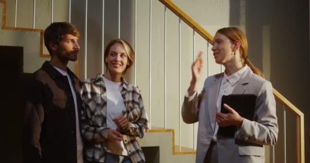 O agente imobiliário mostra uma casa moderna para um jovem casal de aparência europeia — Vídeo de Stock