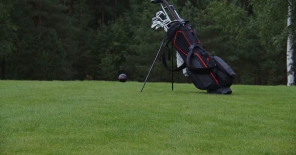 Un hombre clava una camiseta en el suelo y coloca una pelota de golf en ella — Vídeos de Stock