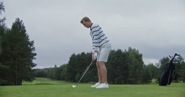 Snygg blond ung man spelar golf på ett stort fält ensam — Stockvideo