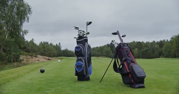 Σακούλες γκολφ γεμάτες με μπαστούνια του γκολφ σταθεί σε ένα περιποιημένο γήπεδο γκολφ — Αρχείο Βίντεο