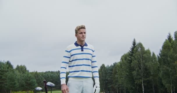 Un joven toma prismáticos de una bolsa de golf y mira a la distancia — Vídeo de stock