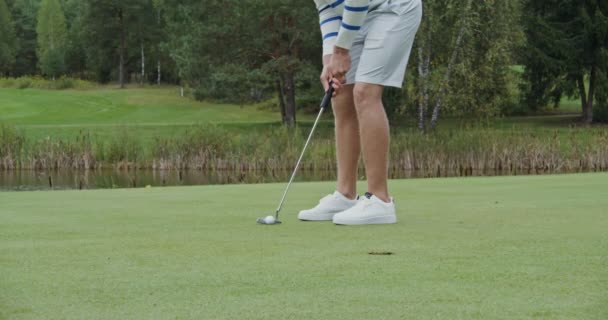 Mężczyzna uderza piłkę kijem golfowym, próbując trafić w dziurę, ale chybia. — Wideo stockowe