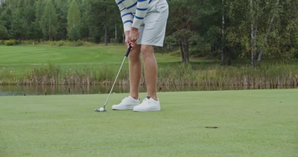 Gros plan d'une balle de golf percutant un trou, l'homme frappe la balle avec un club de golf — Video