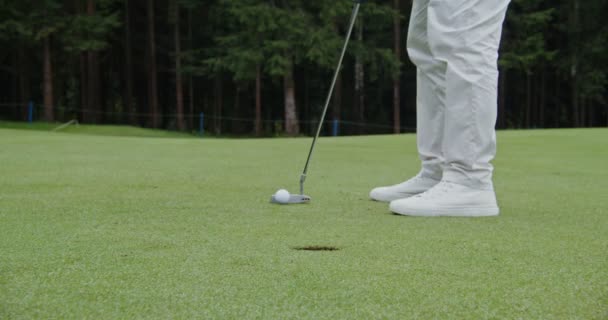 Un hombre no identificado clava una pelota de golf en un hoyo con un palo de golf, de cerca — Vídeo de stock