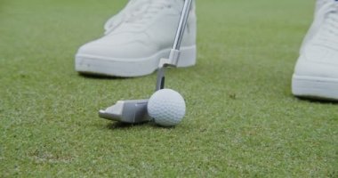 Kimliği belirsiz bir adam golf topuna sopayla vuruyor, yakın plan..