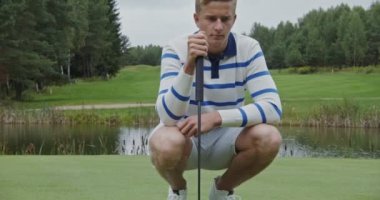 Golf topunun önündeki genç adam deliğe olan mesafeyi hesaplıyor.