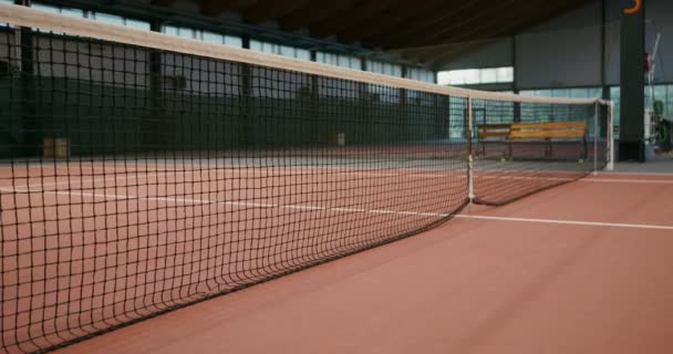 空の屋内テニスコートでプレーするための網を伸ばし — ストック動画