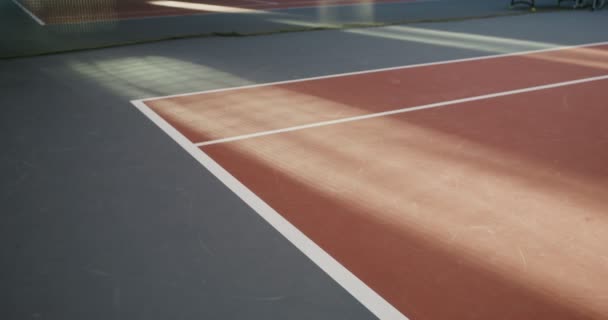 Un hombre caminando en una cancha de tenis, haciendo girar la raqueta de tenis en sus manos, de cerca — Vídeos de Stock