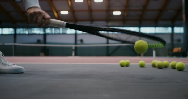 Un sacco di palle da tennis si trovano sul pavimento gommato del campo da tennis al coperto — Video Stock